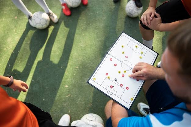 Entrenador explicando la táctica en una pizarra durante el entrenamiento